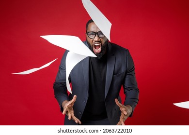 Angry Young Black Business Man 20s Wearing Classic Jacket Suit Eyeglasses Standing Throwing Out Papers Document Screaming Swearing Isolated On Bright Dark Red Plain Color Background Studio Portrait