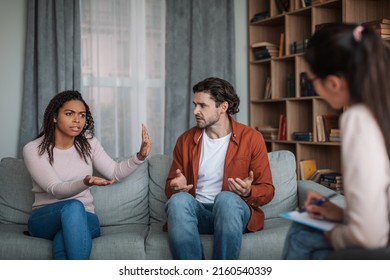 Angry Young Black Wife Ignoring European Husband On Consultation With Psychiatrist In Clinic Interior. Stop Gesture, Quarrel, Treatment, Psychological Problems, Family Therapy And Medical Support