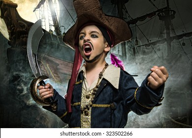 Злой мальчик в пиратском костюме. Он стоит на фоне корабля