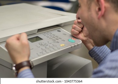 angry young business man beats his fist on a multifunction printer or copier - Shutterstock ID 1043775364