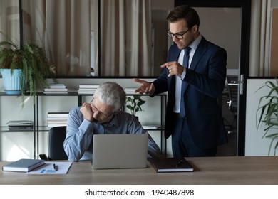 Angry young Caucasian male boss or CEO lecture scold middle-aged employee at workplace. Mad 30s businessman have fight quarrel with senior worker, correct mistakes errors. Discrimination concept.