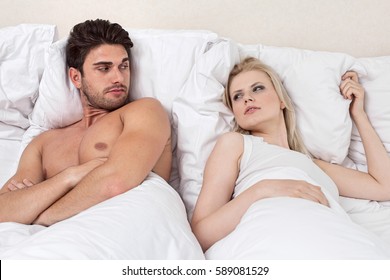 Angry Young Couple Looking At Each Other In Bed