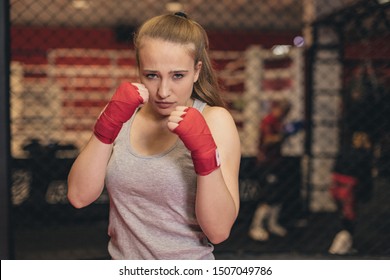 angry  young fighter woman with his hands wrapped in Boxing bandages standing in a boxing stance. Confident caucasian girl is ready for a fighting training.  - Powered by Shutterstock