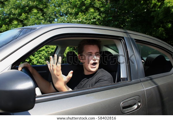 Angry\
young male driver yelling and gesturing to\
someone
