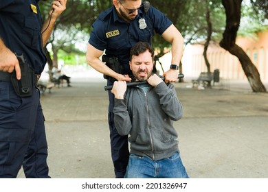 Angry Young Man Criminal Resisting The Arrest While Trying To Escape Of The Police Officers And Fighting A Cop Using A Baton