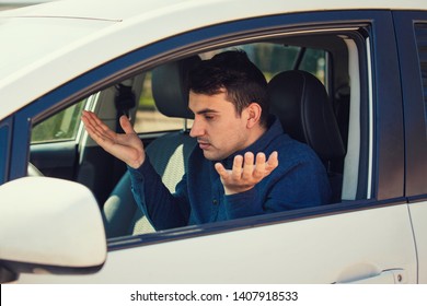 Angry young man driver, pissed off shaking hands and shrugging shoulders, has problems with the car. Displeased perplexed guy has a road accident. Traffic jam rush hour.