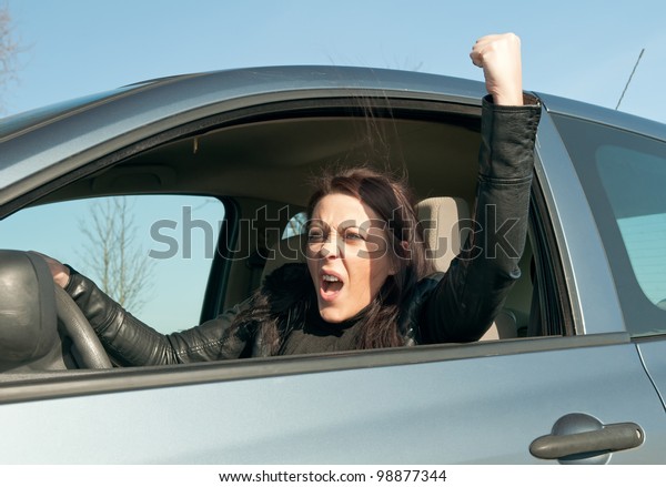 angry young woman
in the car shows the fist