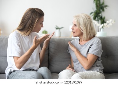 Angry young woman has disagreement with annoyed old mother in law, grown daughter arguing fighting quarreling with senior elderly mom, different age generations bad relations family conflict concept