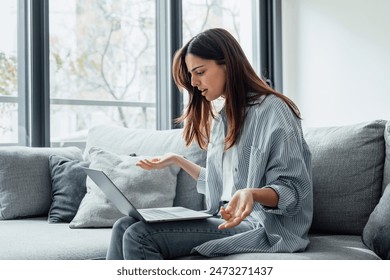 Angry young woman sit on sofa in living room frustrated having operational problems working on laptop, mad millennial girl feel stressed confused with slow internet connection or computer spam