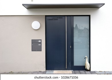The angular and modern house entrance of a residential building with a steel door and a shelter.                          