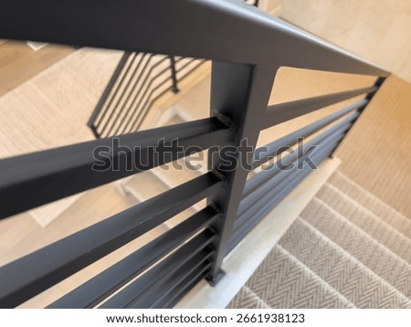 Angular perspective of black stair railing with patterned carpeted stairs below, highlighting geometric design and modern home aesthetics. Great for interior design showcases or real estate catalogs.