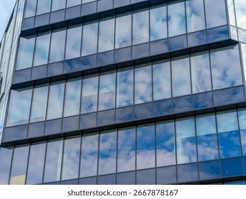 Angular perspective of contemporary glass building facade creating dramatic architectural composition with sky reflection