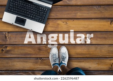 Angular web framework. Legs in shoes standing next to laptop and word Angular 