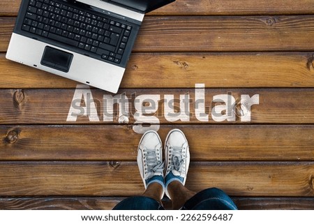 Angular web framework. Legs in shoes standing next to laptop and word Angular 
