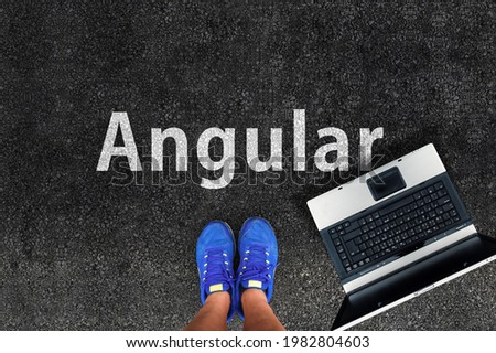 Angular web framework. Legs in sneakers standing next to laptop and word Angular