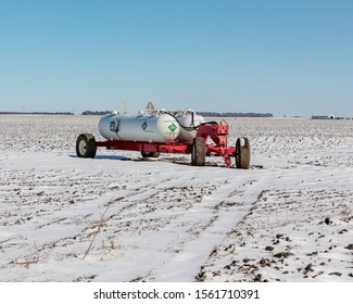 Anhydrous Ammonia Fertilizer Tanks And Wagon In Harvested Soybean Farm Field Covered In Snow After An Early Winter Snowstorm