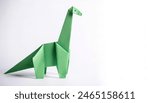 Animal extinct reptile or bird concept origami isolated on white background of a long neck brachiosaurus dinosaur, with copy space, simple starter craft for kids