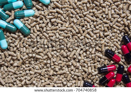 Animal feed pellets and pill capsules as background, antibiotics in livestock feed concept.