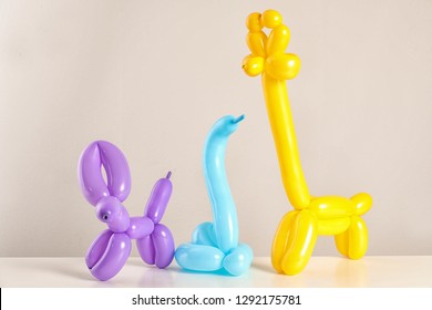 Animal Figures Made Of Modelling Balloons On Table Against Color Background