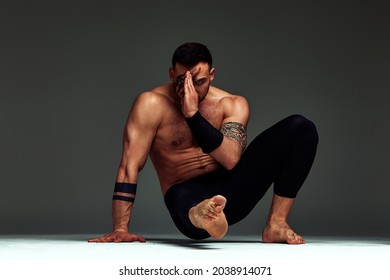 Animal instinct fitness instructor sportsman showing his incredible flexibility with an animal flow move in studio against a gray background