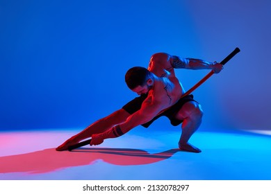Animal instinct fitness instructor sportsman showing his incredible flexibility with an animal flow move in studio against a pink blue gradient background