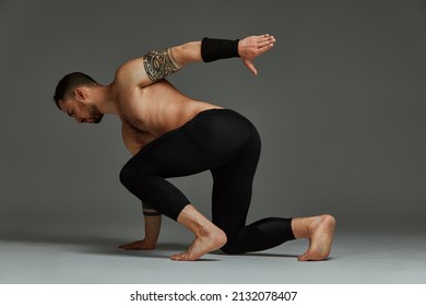 Animal instinct fitness instructor sportsman showing his incredible flexibility with an animal flow move in studio against a gray background