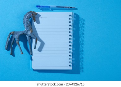 Animal Representation Horse Paper Weight With Blank Note Pad  On Blue Background