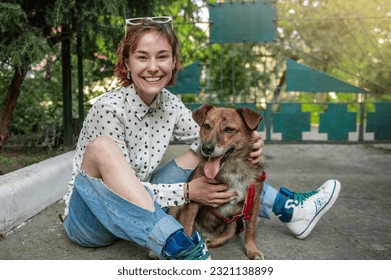 Animal shelter volunteer with dogs. Dog at the shelter. Lonely dogs in cage with cheerful woman volunteer - Powered by Shutterstock