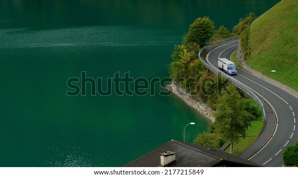 Animal transporting truck driving on a\
twisty road in\
Switzerland.