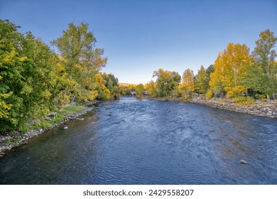 The Animas River flowing through Durango, Colorado surrounded by fall foliage near sunset