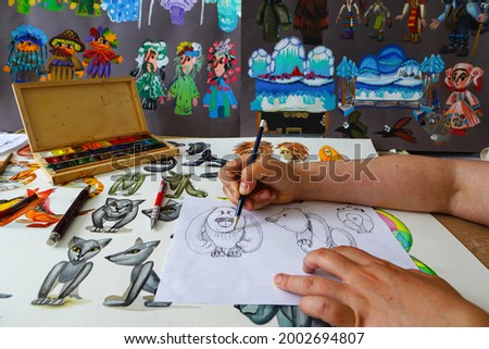 The animator draws with a pencil and draws characters from cartoons, comics or puppet shows. Preparing to make a doll. The designer creates sketches. Comics, cartoons, puppet theater