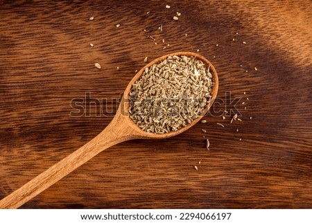 Anise seeds on wooden rustic spoon. Up view studio shoot on wooden background.