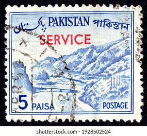 Ankara, Turkey - 3 March 2021: A Pakistan postage stamp shows Khyber Pass, on the border with Afghanistan and red overprinted. Circa 1961. Canceled by seal...