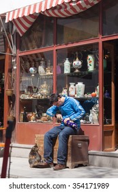 ANKARA, TURKEY - APRIL 09, 2009 :Turkish Shop Keeper Works With A Vase Outside His Store, With Cat By His Feet