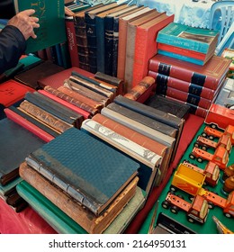 Ankara,  Turkey-February 3, 2019: Group of used vintage books and toy trucks on the showcase at Sunday flea market. Man picking up a book from the stall.