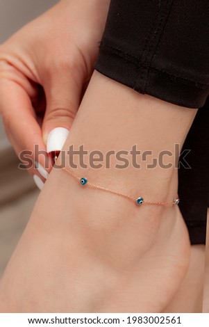 Anklet model shown on the ankle of the lady with white nail polish and black tights.