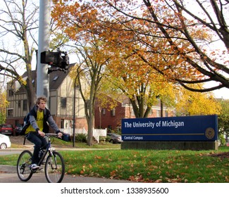 Ann Arbor, Mich./USA-Oct. 25, 2017: A cyclist pedals past a University of Michigan sign on a fall day.                          