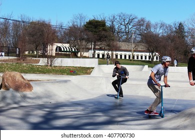 ANN ARBOR, MI/USA: APRIL 5, 2016 Young Men Ride Scooters Stunt At Veterans Memorial Park Skateboard Park On Sunny Day.  
