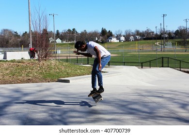 ANN ARBOR, MI/USA: APRIL 5, 2016 Young Black Man In Hat And White T Shirt Skateboards At Veterans Memorial Park On Sunny Day. 