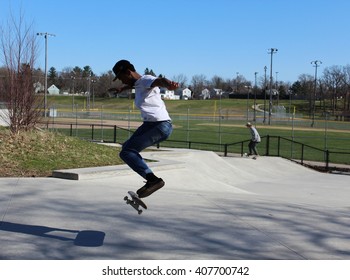 ANN ARBOR, MI/USA: APRIL 5, 2016 Young Black Man In Hat Attempts Stunt At Veterans Memorial Park Skateboard Park On Sunny Day. 