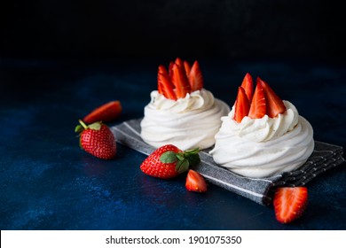 Anna Pavlova cake with cream and fresh strawberries on a dark background, copy space