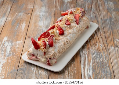 Anna Pavlova meringue roulade with cream and strawberry, served on a wooden table, overhead view