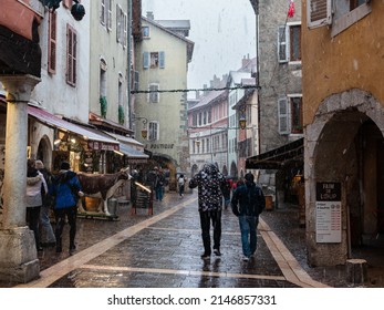 Annecy, France - January 7, 2022: People walking in snowy winter weather in medieval historical old town of french Annecy with colorful facades