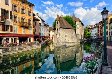 ANNECY, FRANCE - JUNE 22: People drink coffee near the River Thiou in Old Town, encircling the medieval palace perched mid-river - the Palais de l'Isle on June 22, 2014 in Annecy, France. 