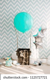 Anniversary Or Birthday Photo Zone With A Large Blue Balloon And A Basket, Silver Stars And A Birthday Cake. Colorful Balloons Background, One Year. Number One. Festive Concert