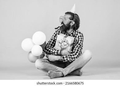 anniversary. have a happy holiday. party time. happy birthday to you. bearded mature man celebrate birthday party. cheerful man in bday hat hold holiday balloons. gifts and presents concept