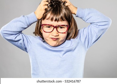 Annoyed 6-year Old Little Child With Eyeglasses Scratching Her Head For Small Tantrum Or Pulling Out Her Hair For Itchy Lice Or Allergies, Grey Background 