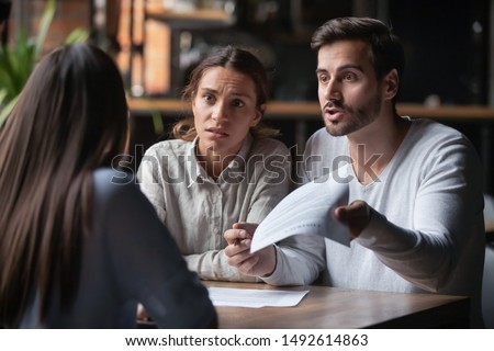 Annoyed angry disappointed customers clients couple holding paper arguing with bank manager fight complain on bad contract terms high mortgage rate demand claim insurance compensation meeting lawyer