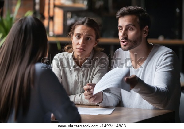 Annoyed angry disappointed customers clients\
couple holding paper arguing with bank manager fight complain on\
bad contract terms high mortgage rate demand claim insurance\
compensation meeting\
lawyer