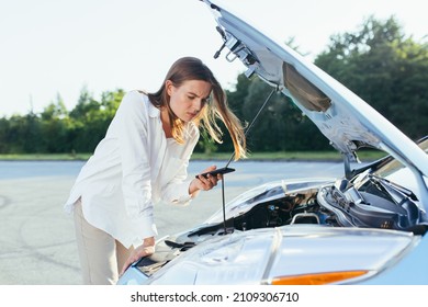 An annoyed and angry woman, near a broken car, tries to call an insurance agent and a repair crew. for car repair - Powered by Shutterstock